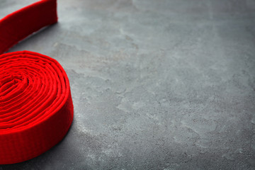 Red karate belt on grey background
