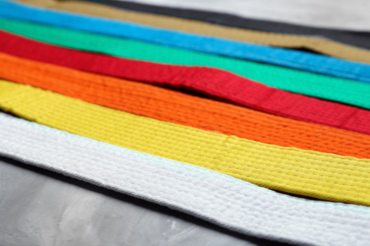Colorful karate belts on grey background, closeup