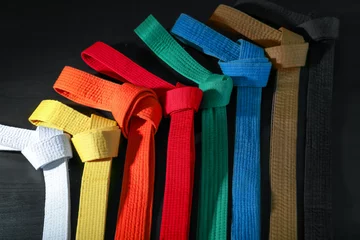 Fotobehang Colorful karate belts on dark background © Africa Studio