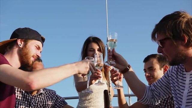Group of friends toasting and clanging glasses during the yacht cruise. Relaxing water trip