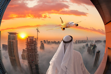 Fototapeta premium Arabski mężczyzna ogląda samolot lecący nad Dubajem w Zjednoczonych Emiratach Arabskich