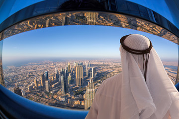 Obraz premium Arabian man watching cityscape of Dubai with modern futuristic architecture in United Arab Emirates.