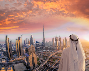 Obraz premium Arabski mężczyzna ogląda panoramę Dubaju z nowoczesną futurystyczną architekturą w Zjednoczonych Emiratach Arabskich.