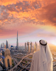 Fototapeta premium Arabian man watching cityscape of Dubai with modern futuristic architecture in United Arab Emirates.