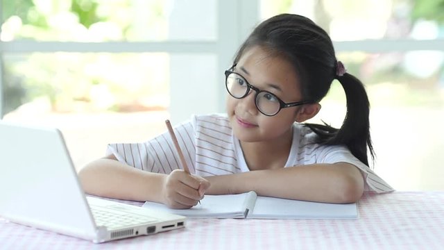 Beautiful asian girl wear glasses writing to notebook on the table slow motion 1