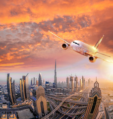 Fototapeta premium Samolot leci nad Dubajem przed kolorowym zachodem słońca w Zjednoczonych Emiratach Arabskich