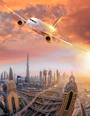 Obraz premium Airplane is flying over Dubai against colorful sunset in United Arab Emirates