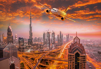 Naklejka premium Airplane is flying over Dubai against colorful sunset in United Arab Emirates