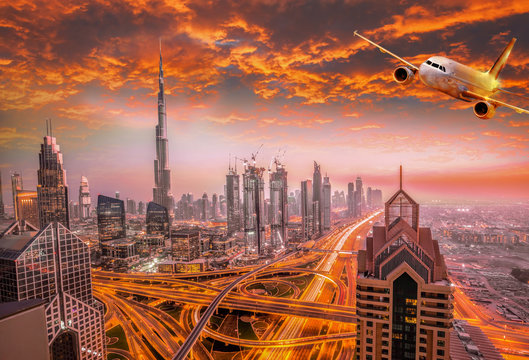 Airplane is flying over Dubai against colorful sunset in United Arab Emirates