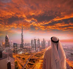 Wall murals Burj Khalifa Arabian man watching cityscape of Dubai with modern futuristic architecture in United Arab Emirates.