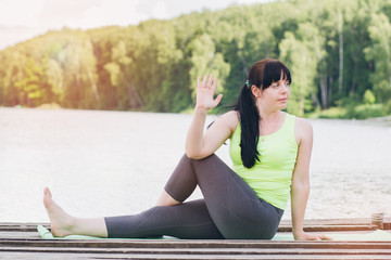 Woman does yoga on the bridge in the summer