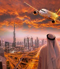 Poster Arabian man with airplane flying over Dubai against colorful sunset in United Arab Emirates © Tomas Marek