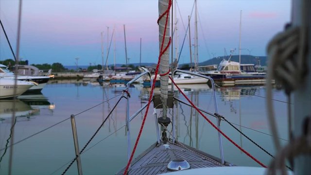 View from the front deck of the sailboat to the evening harbour with yachts at anchor