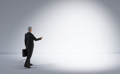 toy miniature businessman figure standing and looking at bright empty white lit space, concept background