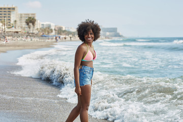 Pretty afro american girl walking into sea looking away