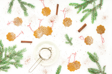 Christmas cookie, pine cone, sugar powder, pine tree branches, cinnamon on white background. Flat lay, top view, christmas background.