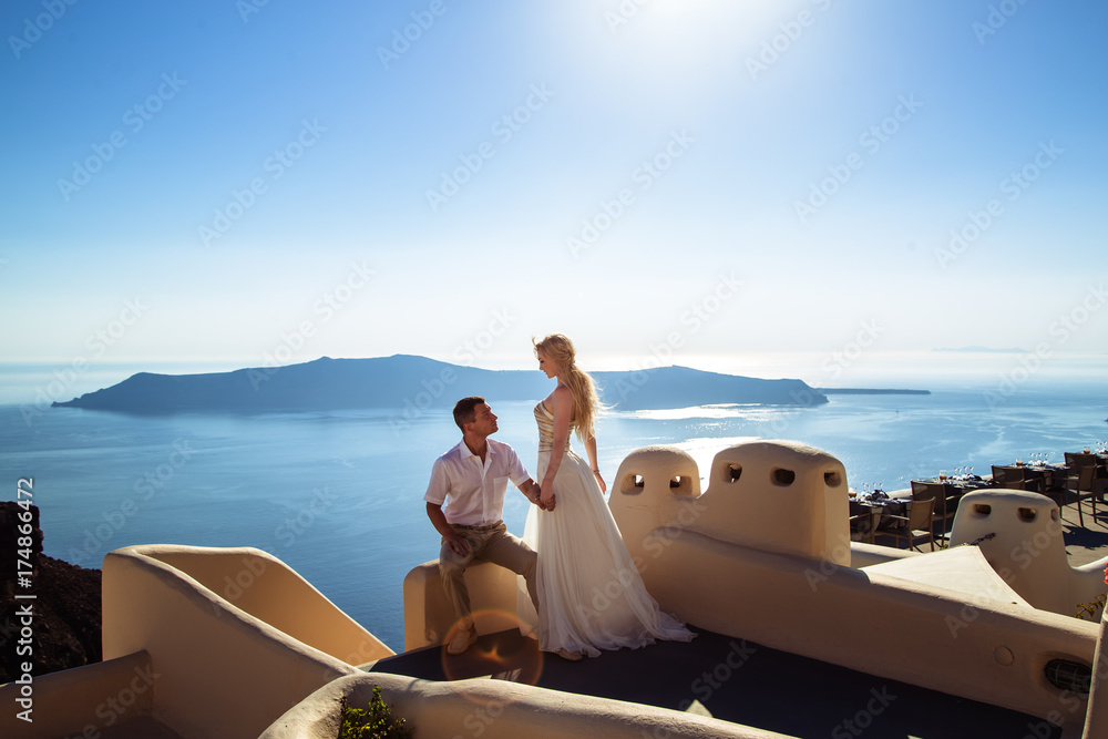 Wall mural beautiful bride and groom in their summer wedding day on greek island santorini