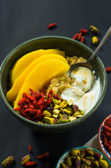 Quinoa porridge with mango, pistachio nuts, goji berries and honey yogurt