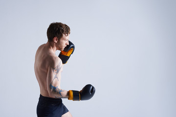 Hardworking young unshaven young European boxer exercising in studio, challening himself, having...