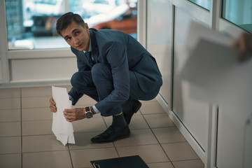 Clerk picks up papers/ Manager of the office employee in a business suit collects the documents falling on the floor listening to the directions of the head.