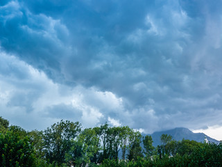 Obraz premium Thunderstorm clouds over trees and bell tower, Belluno, Veneto, Italy