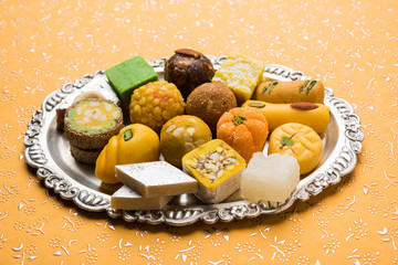 Stock photo of Indian sweets served in silver or wooden plate. variety of Peda, burfi, laddu in decorative plate, selective focus