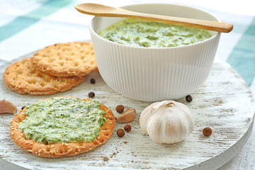 Bowl and cookies with tasty spinach sauce on wooden board