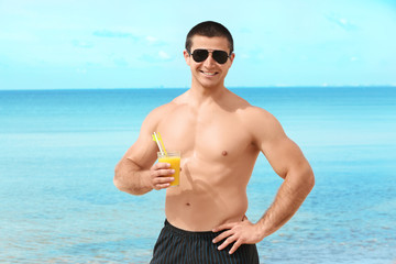 Handsome young man with drink on sea beach