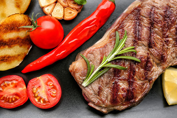 Tasty grilled steak on dark background