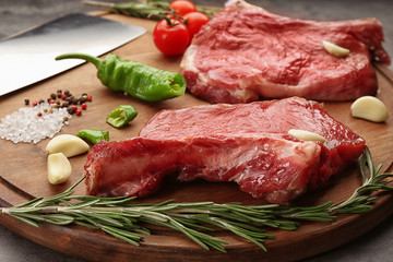 Two raw steaks with rosemary and vegetables on kitchen table
