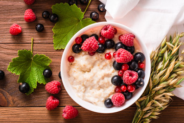 Ready-to-eat oatmeal with fresh raspberries and black currants. Top view