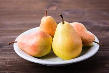 A few pears on a plate on a wooden table