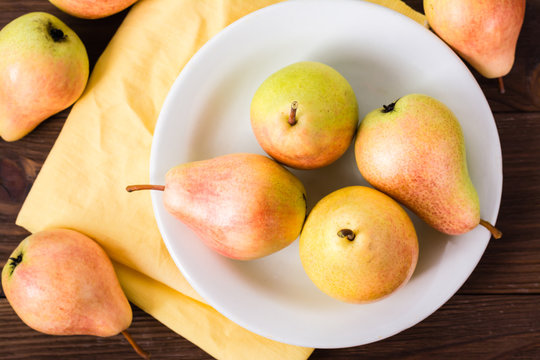 Close-up of ripe pears on a plate on a wooden table. Top view