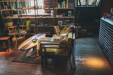 Young pretty caucasian woman reading book in cafe wearing eyeglasses