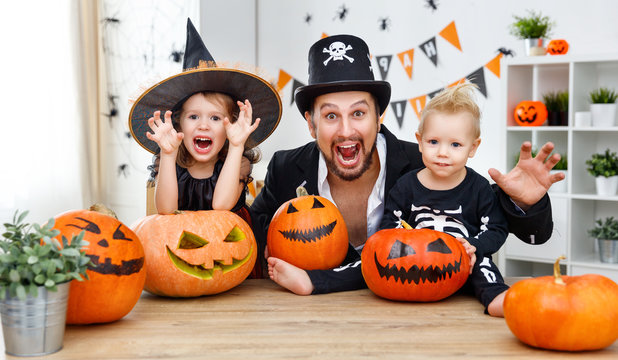 family father and children in costumes   to halloween with pumpkin