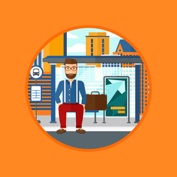 A hipster man with the beard waiting for a bus at a bus stop on a city background. Young man sitting at the bus stop. Vector flat design illustration in the circle isolated on background.