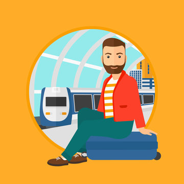 A hipster man with the beard sitting on a suitcase at the train station. Young man waiting for a train at the railway platform. Vector flat design illustration in the circle isolated on background.