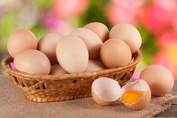 eggs in a wicker basket on a wooden board with blurred garden background