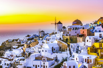 Fototapeta premium Oia town, Santorini island, Greece at sunset. Traditional and famous white houses and churches with blue domes over the Caldera, Aegean sea.