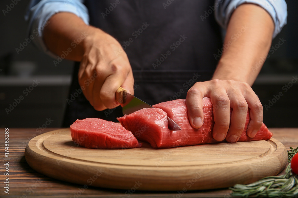 Sticker chef cutting fresh raw meat on wooden board