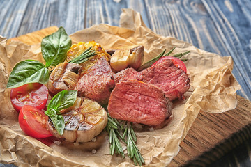 Tasty juicy meat with vegetables on wooden board