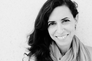 Portrait of smiling beautiful 40 years old woman standing against of city grey wall