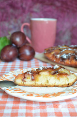 Homemade plum pie, autumn dessert with fresh plums, baking, healthy vegetarian food, a piece of cake on a plate, a cup of tea on a table