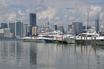 Fototapeta na wymiar A wide variety of recreational boats moored at a Key Biscayne marina with Miami condo and commercial building skyline in the background.