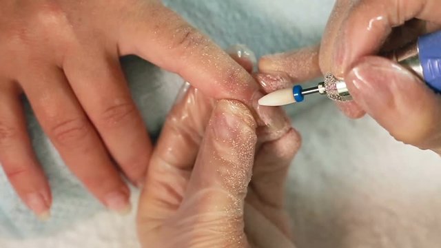 Manicurist removing the old gel polish using nail file. the removal of the gel cutter tool