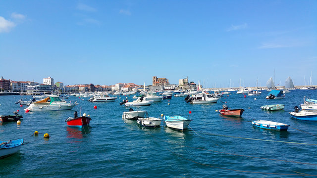 parking of boats and yachts in the bay in Castro-Urdiales, Cantabria, North Spain, against the backdrop of the city center and the old fortress with a lighthouse on a high cliff
