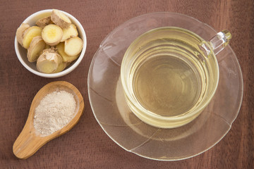 Fresh sliced ginger root and ground ginger on wooden background - Zingiber officinale