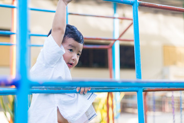 Obraz premium Asian boy hang the metal bar at outdoor playground.