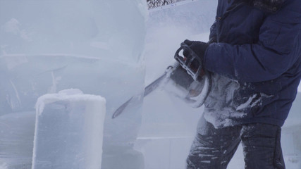 View of sculptor carving ice. Movement. Cut ice with a chainsaw. Cut and make snow sculpture. Chopping iced water with an axe. Ice Sculpture Carving. V-LOG