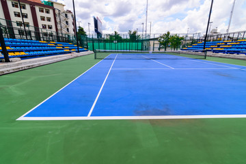 Blue tennis court with  lines. Clouds blue sky background.